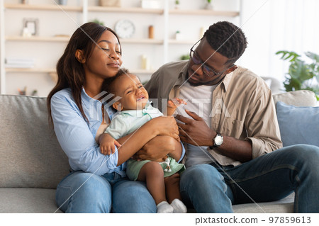 African American parents sitting with crying kid on sofa African American parents sitting with crying kid on sofa 97859613