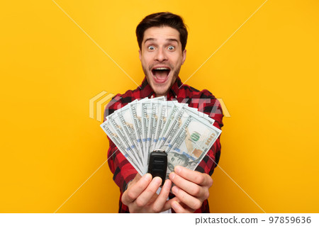 Excited Guy Showing Car Key And Money Cash, Yellow Background Excited Guy Showing Car Key And Money Cash, Yellow Background 97859636