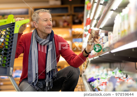Happy male pensioner buying food at supermarket Happy male pensioner buying food at supermarket 97859644