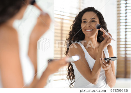 Makeup Routine. Cheerful Young Lady Applying Blush With Brush Near Mirror Makeup Routine. Cheerful Young Lady Applying Blush With Brush Near Mirror 97859686