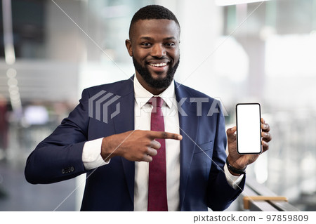 Positive black businessman pointing at smartphone with empty screen Positive black businessman pointing at smartphone with empty screen 97859809