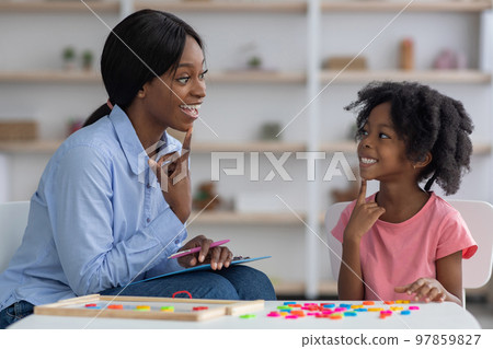 African american speech therapist working with little girl at clinic 97859827