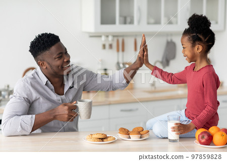 Positive african american father and daughter having snack 97859828