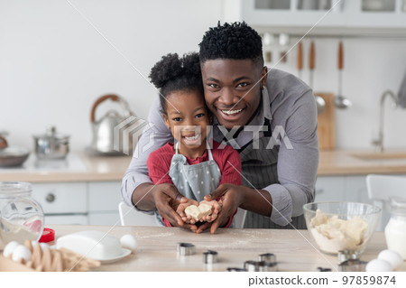 Happy black father and daughter making cookies in heart shape Happy black father and daughter making cookies in heart shape 97859874