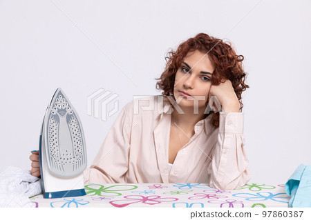 A girl worried about the next batch of shirts to be ironed. A girl worried about the next batch of shirts to be ironed. 97860387