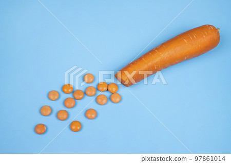 Orange vitamin D pills and a carrot 97861014