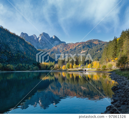 Peaceful autumn Alps mountain lake with clear transparent water and reflections. Gosauseen or Vorderer Gosausee lake, Upper Austria. Dachstein summit and glacier in far. 97861326