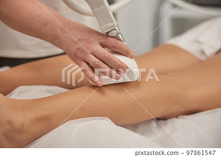 Fighting overweight, roller massage, Hardware correction. Professional beauty clinic, young woman doing beauty services, body shaping, masseur giving vacuum roller massage to client, figure correction 97861547