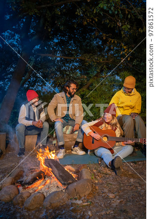 Group friends having fun laughing and singing around the bonfire camping youth friendship concept 97861572