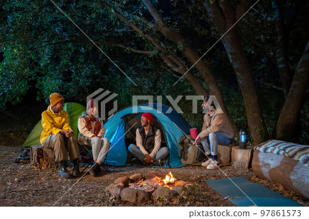 Group of multiethnic friends happy around the bonfire camping hike trekkers excursion in the nature Group of multiethnic friends happy around the bonfire camping hike trekkers excursion in the nature 97861573