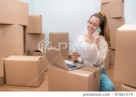 Beautiful girl with cardboard boxes unpacking in new home - Working with laptop Beautiful girl with cardboard boxes unpacking in new home - Working with laptop 97861574