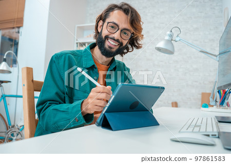 Young designer looking at camera while working with graphics tablet 97861583