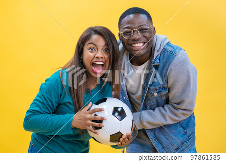 Excited ethnic diversity couple enjoying soccer together isolated on yellow background happy. 97861585