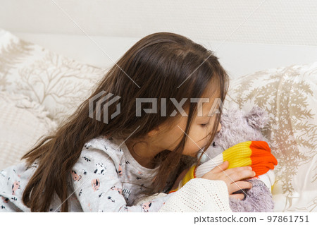 Little girl measure temperature by kissing forehead of sick teddy bear. Doctor, play with stuffed toy, treatment. 97861751