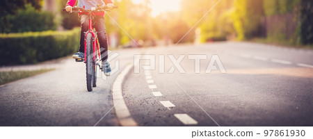 Boy riding a bike on the sidewalk along asphalt road. Boy riding a bike on the sidewalk along asphalt road. 97861930