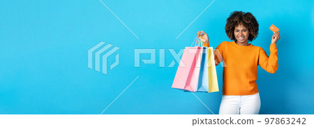 Black woman in casual holding shopping bags and credit card Black woman in casual holding shopping bags and credit card 97863242