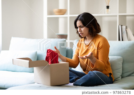 Wrong Parcel. Confused arab woman looking at open cardboard box at home 97863278