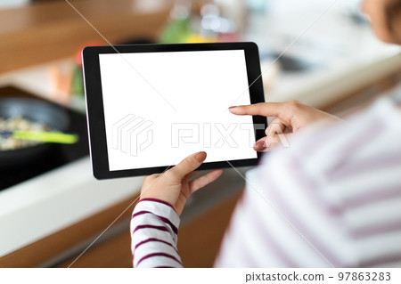 Cropped of woman cooking at home, using digital tablet, mockup Cropped of woman cooking at home, using digital tablet, mockup 97863283