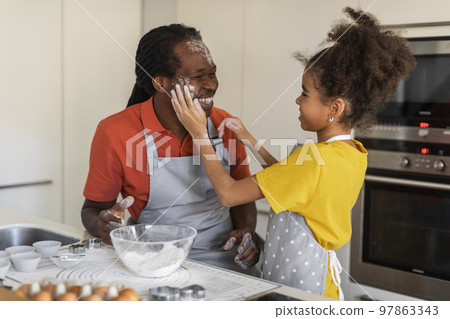 Cheerful Black Girl Playing With Dad In Kitchen While They Baking Together 97863343