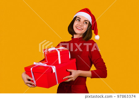 Happy young woman in Santa hat holding xmas presents Happy young woman in Santa hat holding xmas presents 97863374