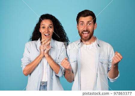 Satisfied excited surprised young european male and arab lady make sign of victory and success with hands 97863377
