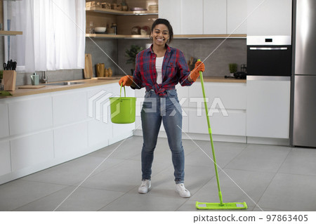 Cheerful millennial african american female in rubber gloves with bucket and mop washes floor 97863405