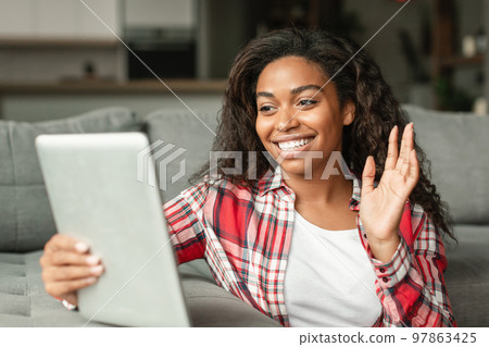 Glad millennial black lady blogger shoots video blog, has online call, makes greeting gesture in smartphone webcam 97863425