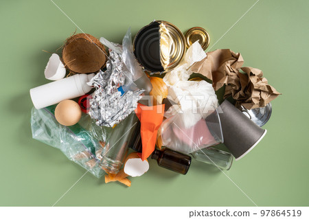Big messy pile of non sorted waste of plastic, metal, foil, organic, paper, glass on green studio background. Top view 97864519
