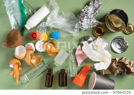 Pile of different of non sorted garbage of plastic, metal, organic, paper, glass on green studio background. Recycling 97864520