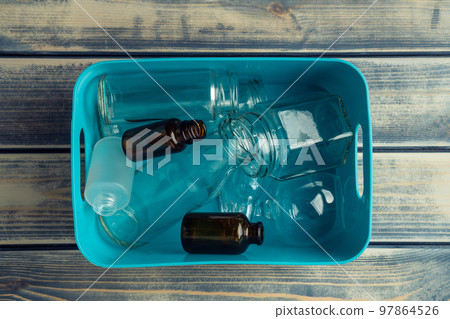 Blue plastic square box full of transparent plastic and glass bottles on wooden background. Nondegradable rubbish crisis Blue plastic square box full of transparent plastic and glass bottles on wooden background. Nondegradable rubbish crisis 97864526