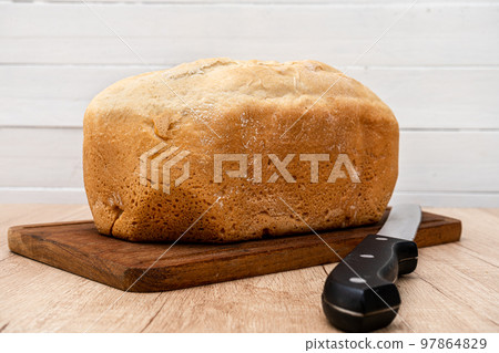 Homemade bread last made with a bread machine on a wooden board with a bread knife. Space for text. Homemade bread last made with a bread machine on a wooden board with a bread knife. Space for text. 97864829