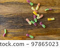 gummy candies scattered on a wooden background, multi-colored gummies 97865023