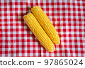 corn a couple of cobs on a checkered tablecloth, white and red square 97865024