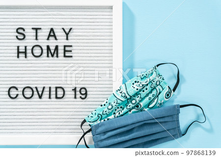 STAY HOME and COVID-19 sign on message board with a homemade face mask. 97868139