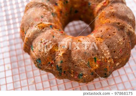 Close up view. Cooling freshly baked funfettti bundt cake on a wire rack. 97868175