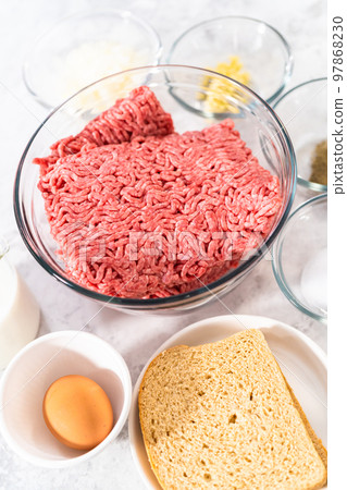 Measured ingredients in glass mixing bowls to make meatloaf. 97868230