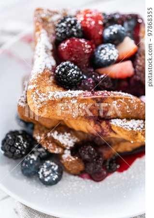 Stack of freshly made french toast garnished with mix berry compote and powder sugar. Stack of freshly made french toast garnished with mix berry compote and powder sugar. 97868355