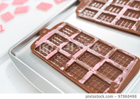 Removing mini pink chocolates from silicone chocolate mold. 97868498