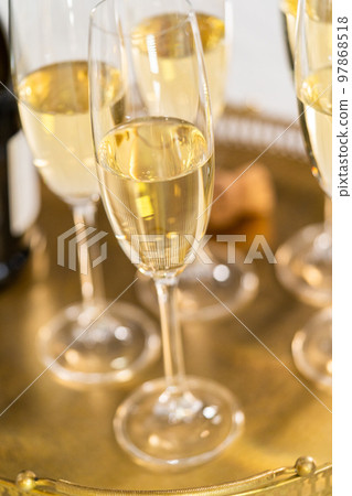 Champagne glasses filled with champagne on a gold tray. 97868518