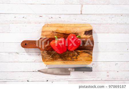 Flat lay. Cutting organic red bell peppers on a wood cutting board. 97869187