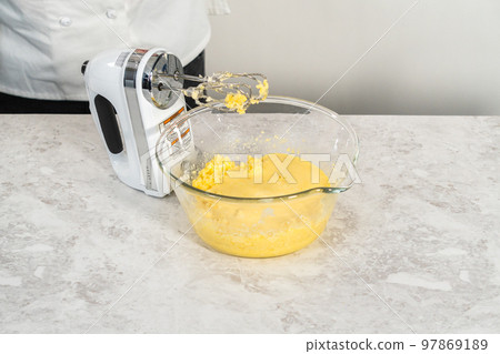 Mixing ingredients in a glass mixing bowl to bake funfettti bundt cake. 97869189