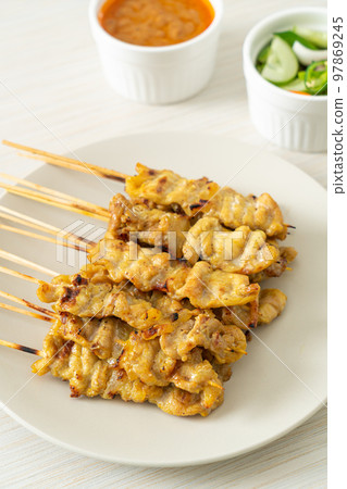 Pork satay with peanut sauce pickles which are cucumber slices and onions in vinegar 97869245