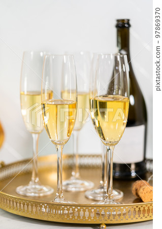 Champagne glasses filled with champagne on a gold tray. 97869370