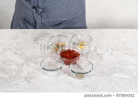 Measured ingredients in glass mixing bowls to make a sweet glaze for meatloaf. 97869382