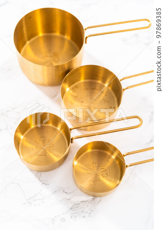 Close-up view. Cupper measuring cups and spoons for baking on a marble countertop. Close-up view. Cupper measuring cups and spoons for baking on a marble countertop. 97869385
