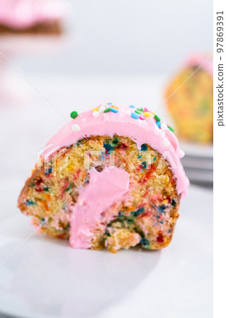 Close up view. Sliced funfettti bundt cake with pink buttercream frosting on top and buttercream filling inside. Close up view. Sliced funfettti bundt cake with pink buttercream frosting on top and buttercream filling inside. 97869391