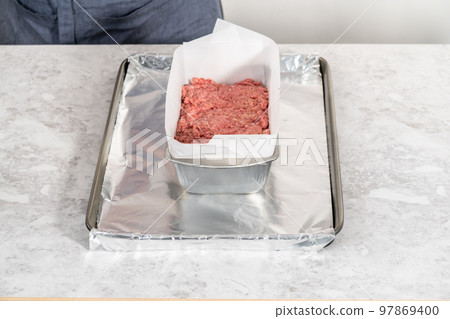 Preparing classic meatloaf in a loaf pan lined with parchment paper. Preparing classic meatloaf in a loaf pan lined with parchment paper. 97869400
