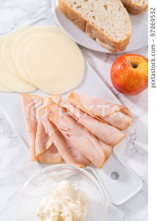 Measured ingredients in a glass mixing bowl to prepare provolone and apple grilled cheese sandwich. 97869532