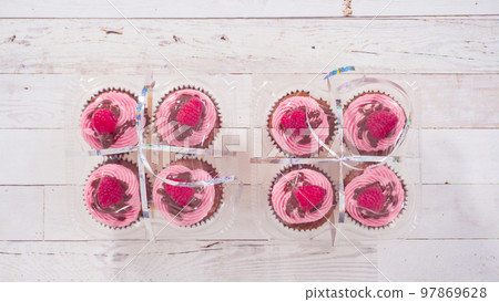 Flat lay. Packaging gourmet chocolate raspberry cupcakes into clear plastic boxes. 97869628