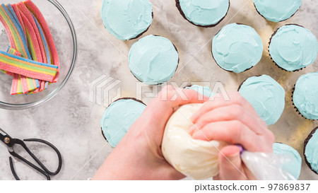 Flat lay. Step by step. Decorating chocolate cupcakes with buttercream frosting and rainbow candy. Flat lay. Step by step. Decorating chocolate cupcakes with buttercream frosting and rainbow candy. 97869837